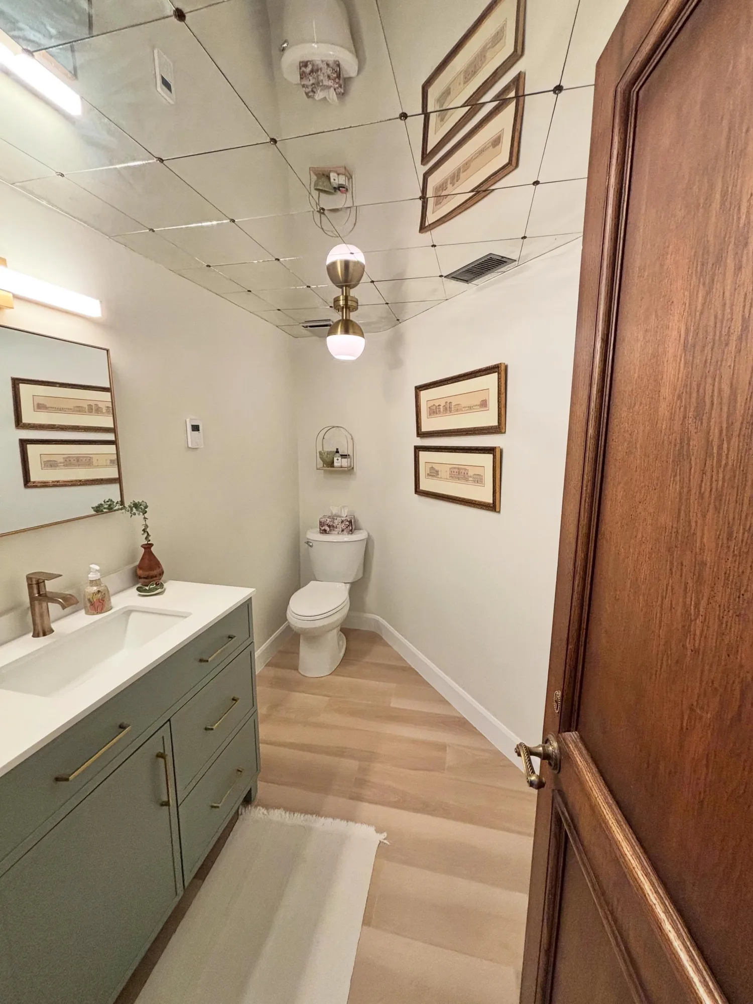 Remodelled powder room with a green vanity and light tile floor