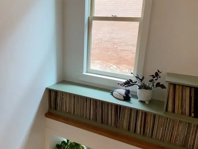 Custom green record shelving fitted beneath a stairwell window